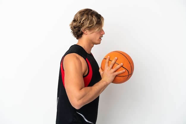 Junger blonder Mann isoliert, der Basketball spielt