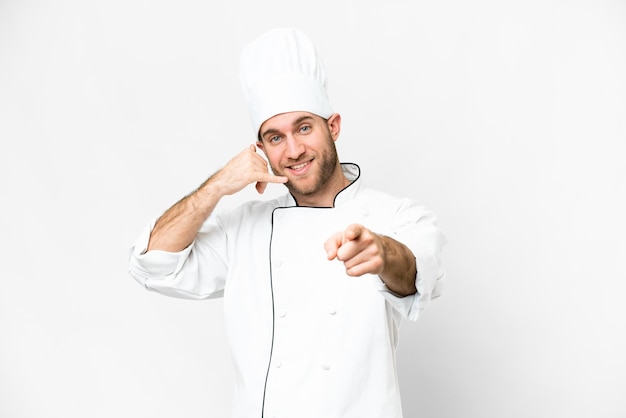 Junger blonder Mann Koch über isoliertem weißem Hintergrund, der eine Telefongeste macht und nach vorne zeigt