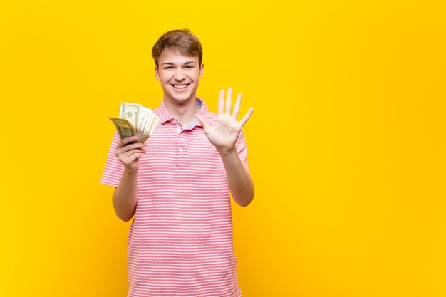 Junger blonder Mann mit Dollarbanknoten