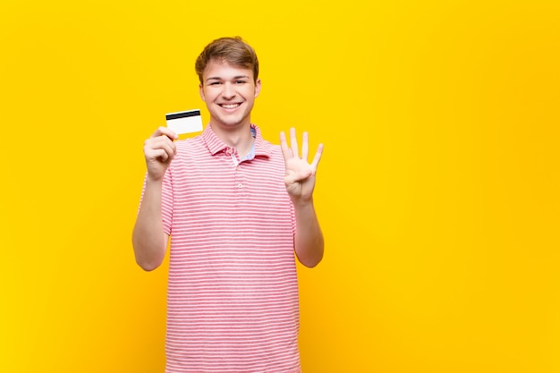 Junger blonder Mann mit einer Kreditkarte