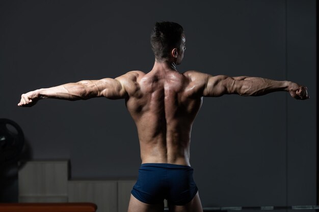 Junger Bodybuilder, der zurück Pose biegt
