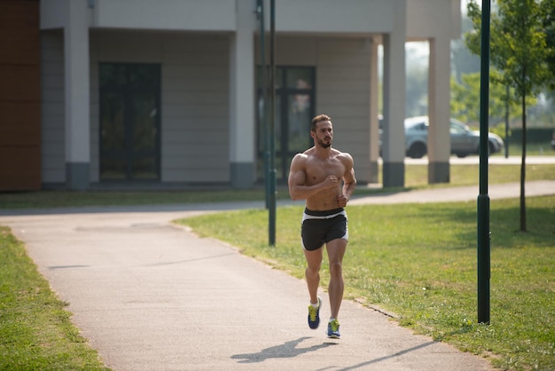 Junger Bodybuilder läuft im Parkbereich Training und Training für Trail Run Marathon Ausdauer Fitness gesunden Lebensstil Konzept