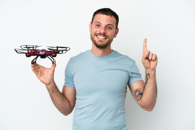 Junger brasilianischer Mann hält eine Drohne isoliert auf weißem Hintergrund und zeigt eine großartige Idee