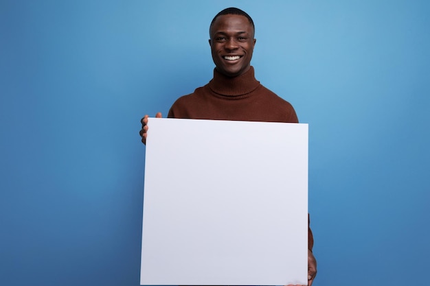 Junger brünetter amerikanischer Mann hält weißes Laken für Werbefläche oder wichtige Ankündigung
