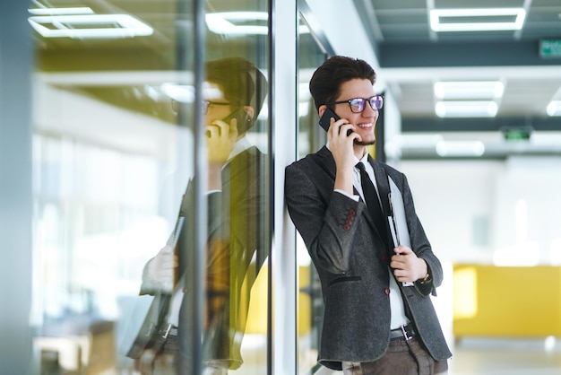 Junger Büroangestellter mit Brille und Smartphone Geschäftsmann hält Telefon in der Hand