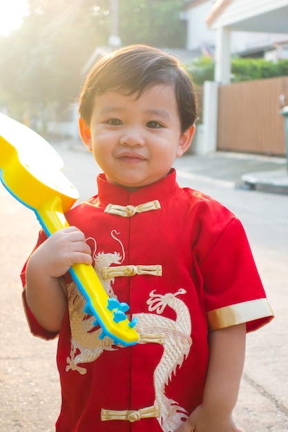 Junger chinesischer Junge, der im chinesischen Kostümkleid des neuen Jahres lächelt und glücklich ist