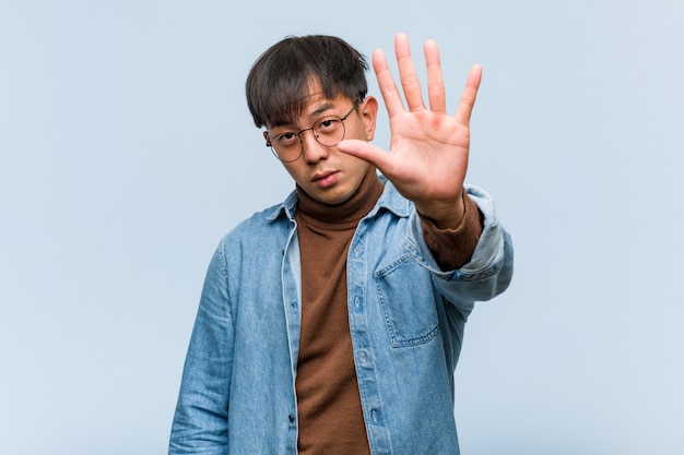 Junger chinesischer Mann, der Hand in Front einsetzt