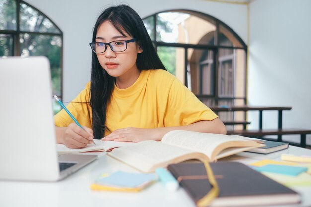 Junger Collage-Student, der Computer und mobile Geräte verwendet, um Online-Bildung und Online-Lernen zu studieren