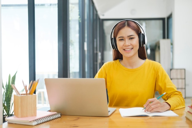 Junger Collage-Student, der Computer und mobiles Gerät verwendet, um online zu studieren