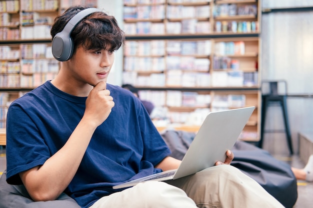 Junger Collagestudent, der Computer und mobiles Gerät verwendet, das online studiert. Bildung und Online-Lernen.