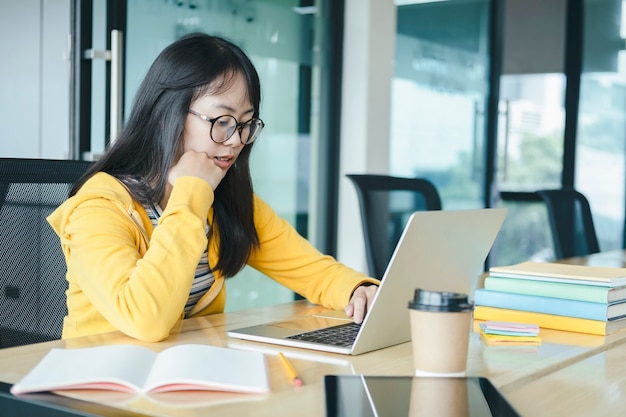 Junger Collagestudent, der Computer und mobiles Gerät verwendet, das online studiert.