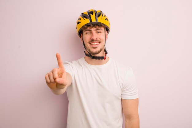 Junger cooler Mann, der lächelt und freundlich aussieht und das Fahrradkonzept Nummer eins zeigt