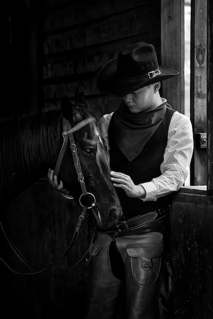 Junger Cowboy und Pferd im Stall auf Schwarzem