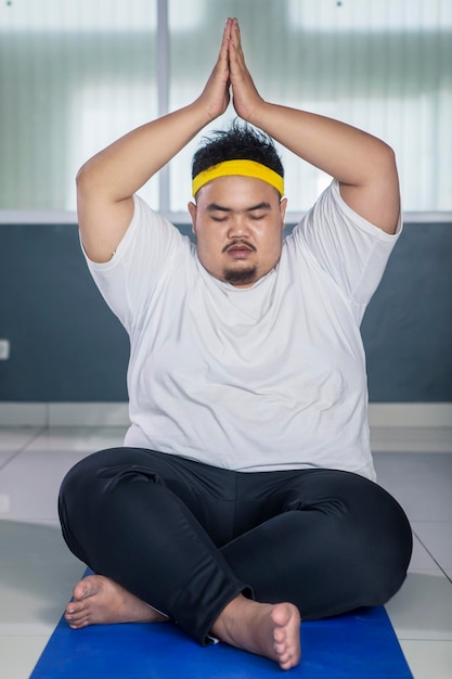Foto junger dicker mann macht yoga-übungen auf der matte