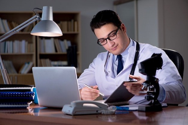 Junger Doktor, der spät im Büro arbeitet