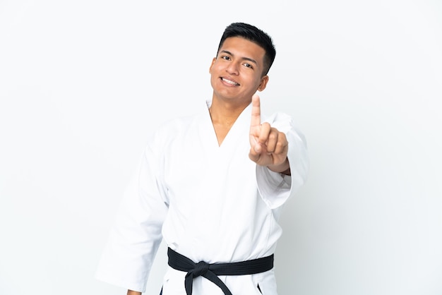 Junger ecuadorianischer Mann, der Karate lokalisiert auf weißer Wand tut, die einen Finger zeigt und hebt