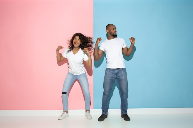 Junger emotionaler Mann und Frau auf rosa und blauem Hintergrund