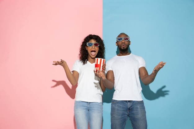 Junger emotionaler Mann und Frau auf rosa und blauem Hintergrund