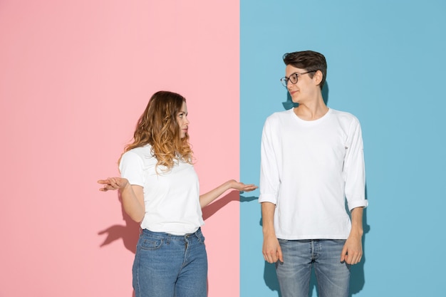 Junger emotionaler Mann und Frau auf rosa und blauem Hintergrund