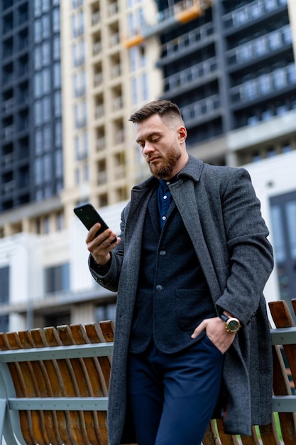 Junger erfolgreicher Geschäftsmann, der Telefon untersucht. Gut aussehender Mann mit seinem Smartphone.