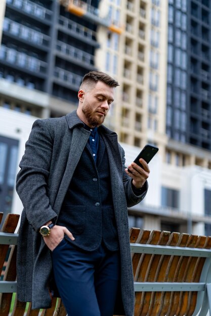 Junger erfolgreicher Geschäftsmann, der Telefon untersucht Schöner Mann mit seinem Smartphone