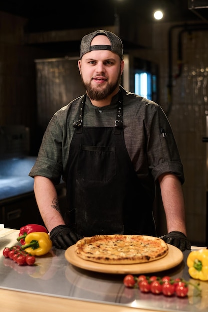 Junger erfolgreicher Koch oder Besitzer eines kleinen Restaurants steht am Arbeitsplatz