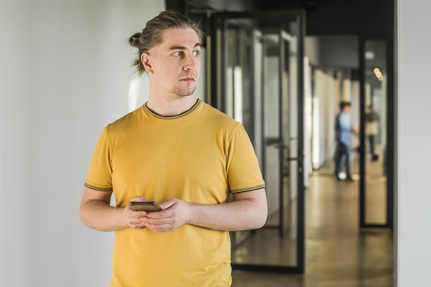 Foto junger ernsthafter mann benutzt mobiltelefon im bürogebäude internet-breitband g porträt eines nachdenklichen mannes