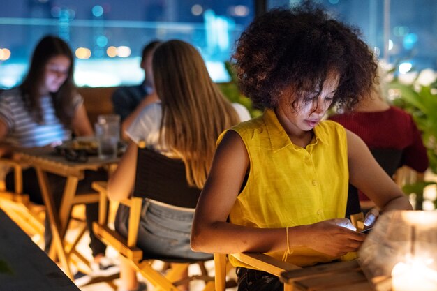 Junger Erwachsener an einem Abendessen unter Verwendung eines Smartphonensuchtkonzeptes