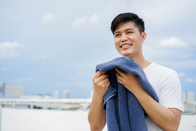 junger erwachsener asiatischer mann, der das blaue handtuch draußen zu hause riecht, nach für den täglichen und routinemäßigen l