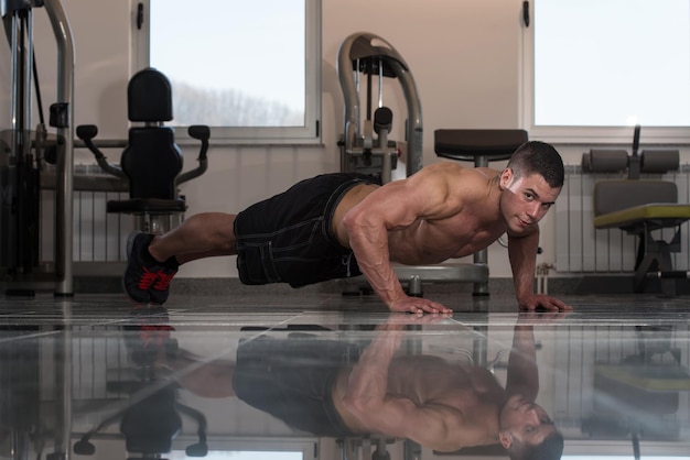 Foto junger erwachsener athlet, der push-ups als teil des bodybuilding-trainings macht