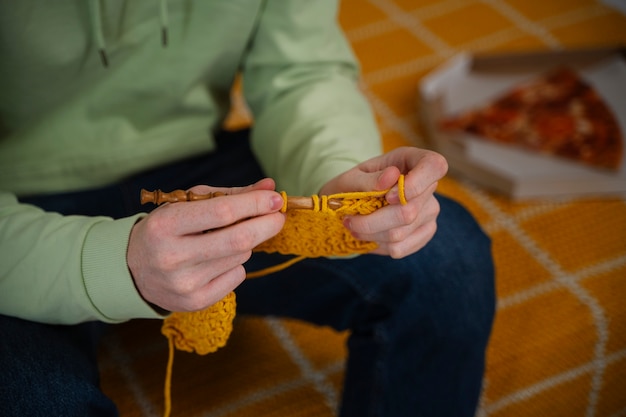 Foto junger erwachsener, der zu hause hohen winkel strickt