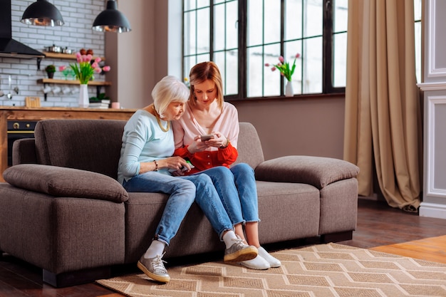 junger erwachsener Freiwilliger diskutiert mit einer alternden Frau auf dem Sofa