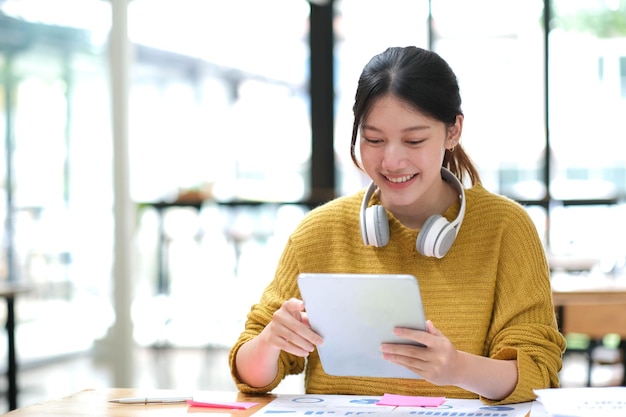 Junger Erwachsener, glücklich lächelnde hispanische asiatische Studentin mit Kopfhörern, die über Online-Chat-Meetings mit Laptops auf dem Universitätscampus oder im virtuellen Büro spricht College-Studentin, die aus der Ferne lernt