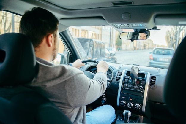 Junger erwachsener mann, der mit dem auto durch die straßen der stadt fährt und das telefon als navigation verwendet. lebensstil