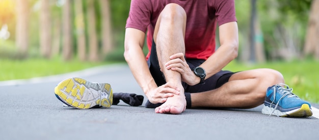 Junger erwachsener Mann mit seinen Muskelschmerzen während des Laufens.