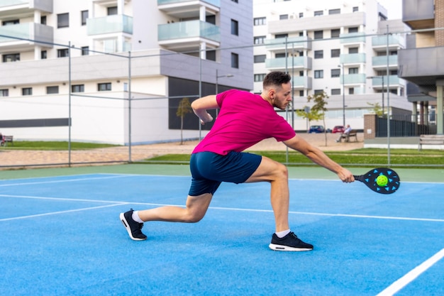 Junger erwachsener Mann spielt Pickleball. Mann führt einen Rückhandschuss in einem Pickleball-Match aus