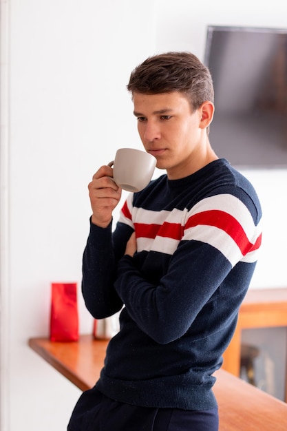 Junger Erwachsener trinkt morgens eine Tasse Kaffee, um einen Tag voller Energie zu beginnen. Lateinischer Mann.