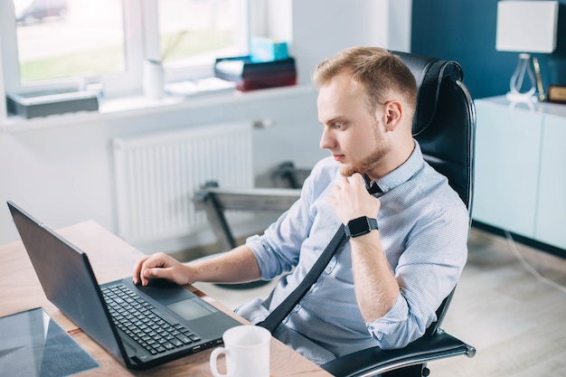 junger europäischer Geschäftsmann arbeitet an einem Laptop in einem modernen hellen Büro