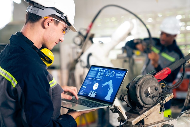 Junger Fabrikarbeiter, der mit einem geschickten Roboterarm arbeitet