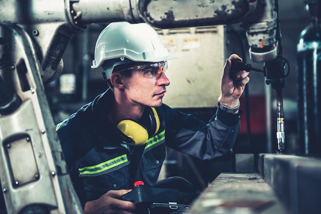 Junger Fabrikarbeiter, der mit einem geschickten Roboterarm arbeitet