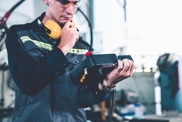 Junger Fabrikarbeiter, der mit einem geschickten Roboterarm arbeitet