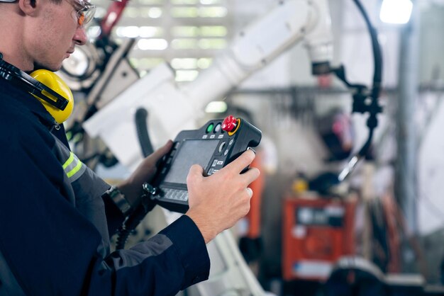 Junger Fabrikarbeiter, der mit einem geschickten Roboterarm arbeitet