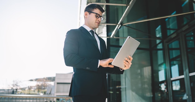 Junger formeller Mann mit Tablette im Sonnenlicht