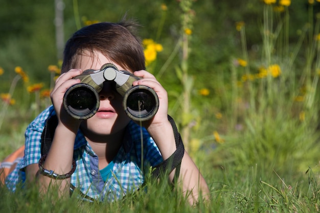 Junger Forscher des Jungen, der mit Fernglasumgebung im Sommergarten erforscht