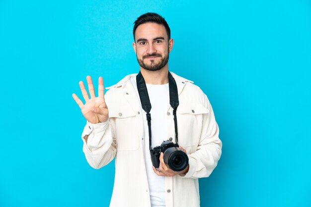 Junger Fotograf Mann lokalisiert auf blauer Wand glücklich und zählt vier mit den Fingern