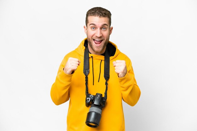 Junger Fotograf über isoliertem weißem Hintergrund, der einen Sieg in Siegerposition feiert