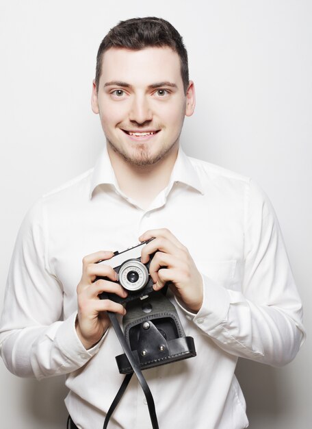 Junger Fotografmann, der mit seiner Kamera aufwirft