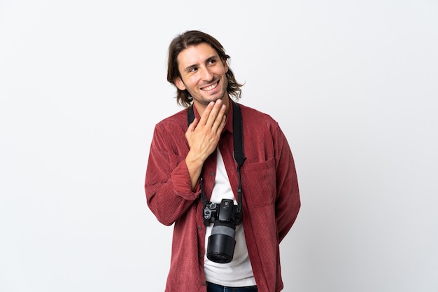 Junger Fotografmann lokalisiert auf weißem Aufschauen beim Lächeln