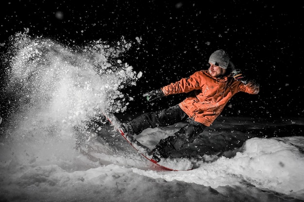 Junger Freeride Snowboarder, der in Schnee nachts springt