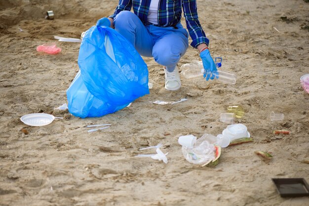 Junger Freiwilliger, der Plastikflaschen am Strand nahe dem Park aufhebt.